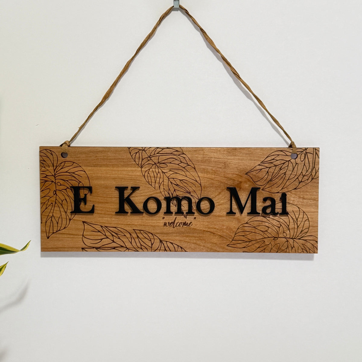 Hawaiian Welcome Sign E Komo Mai Greeting Birch Wood Door Hanger Natural Grain Finish Laser Engraved Text Monstera Leaf Tropical Design Raffia Hanging Display Beach House Styling Coastal Entryway Addition Island Inspired Living Perfect